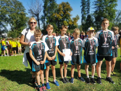 Sześciu uczniów z medalami pozuje do zdjęcia z nauczycielką.