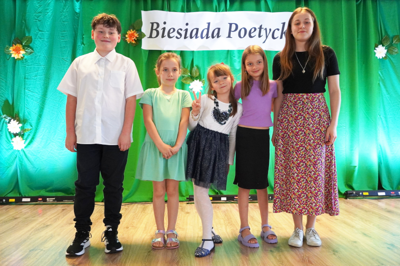 Piątka uczniów reprezentujących Szkołę Podstawową w Bystrej na Biesiadzie Poetyckiej stoi na tle dekoracji.