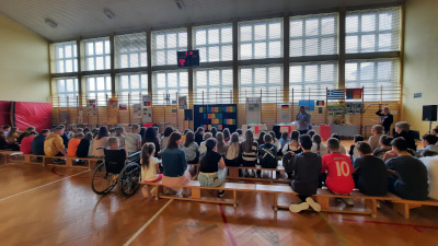 Uczniowie na dniu języków obcych siedzą na ławkach w&nbsp;sali gimnastycznej