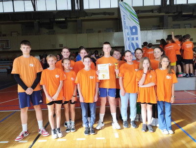 Uczniowie w hali sportowej OSIR w Gorlicach pozują do zdjęcia z dyplomem i pucharem